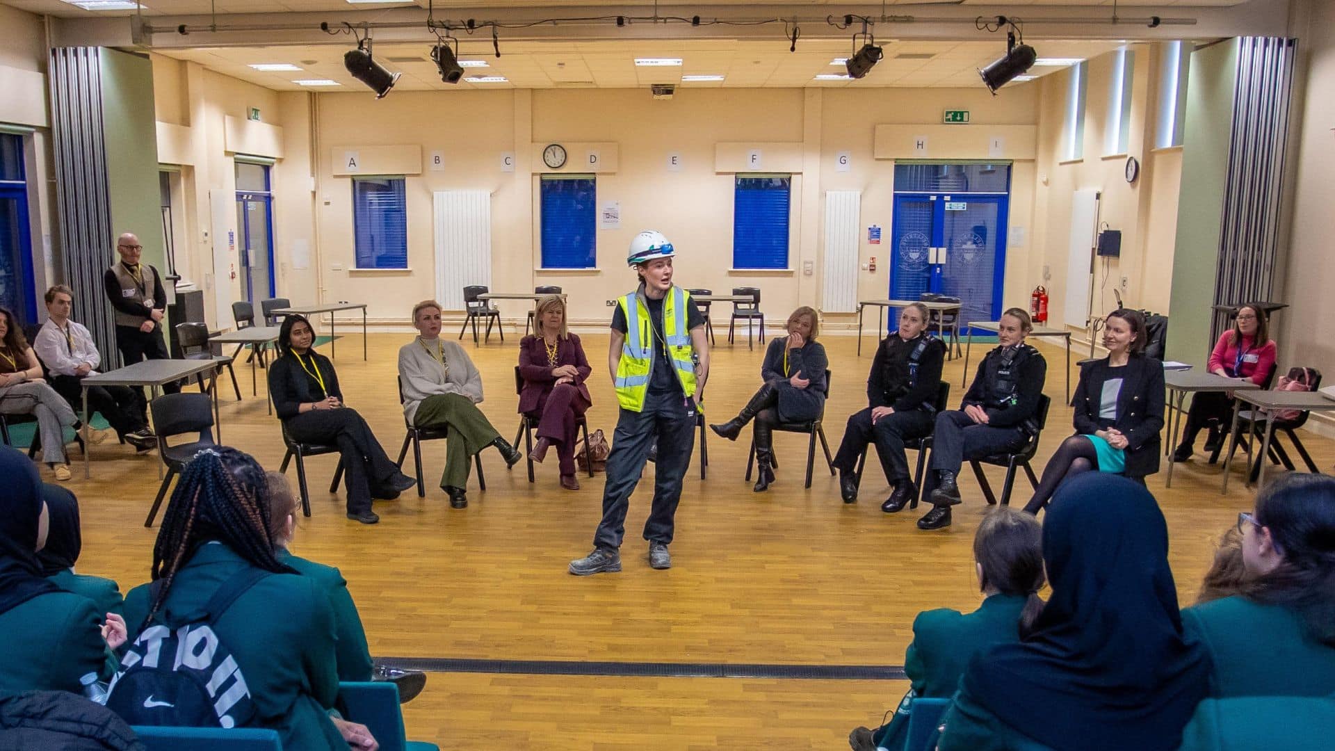 Jessie Brown from construction company Morgan Sindall talks to college students about her job, while wearing her construction gear, including high-vis jacket and hardhat.